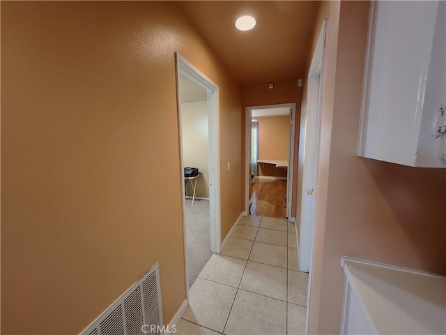 corridor featuring recessed lighting, light tile patterned floors, baseboards, visible vents, and light colored carpet