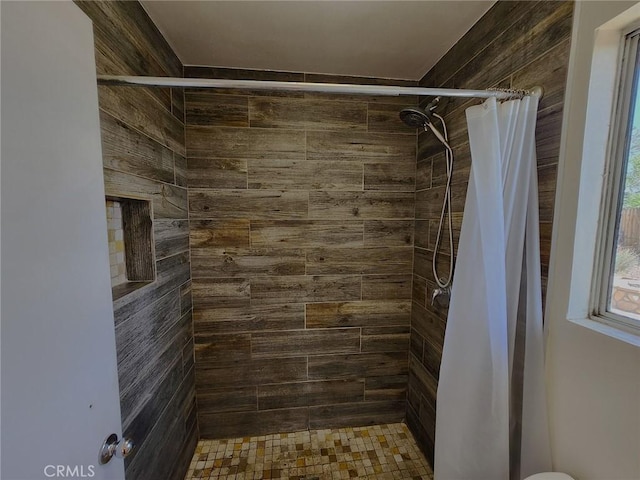 full bathroom featuring wood walls and a tile shower