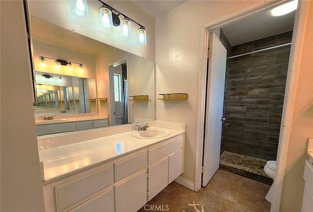 bathroom featuring toilet, a tile shower, tile patterned floors, and vanity
