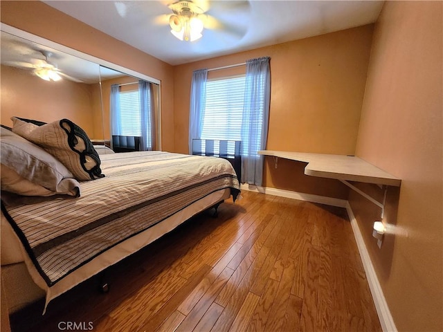 bedroom with baseboards, hardwood / wood-style floors, and a ceiling fan