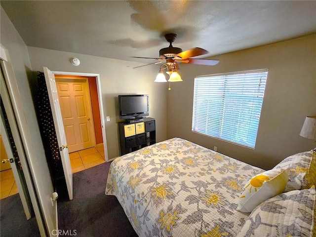 bedroom with ceiling fan, dark tile patterned flooring, and dark carpet