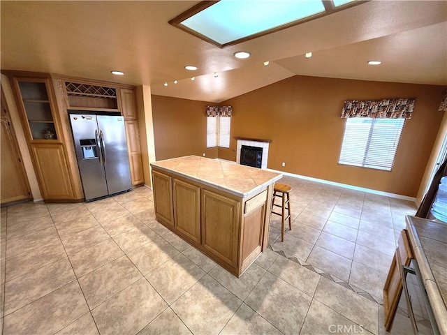 kitchen featuring lofted ceiling, recessed lighting, a tiled fireplace, light tile patterned flooring, and stainless steel refrigerator with ice dispenser