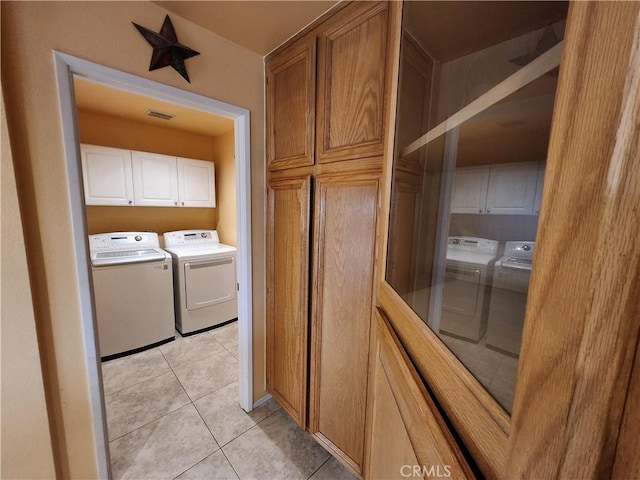washroom featuring visible vents, cabinet space, light tile patterned floors, and washer and dryer