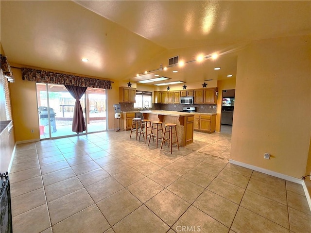 kitchen featuring light tile patterned floors, stainless steel appliances, visible vents, and vaulted ceiling