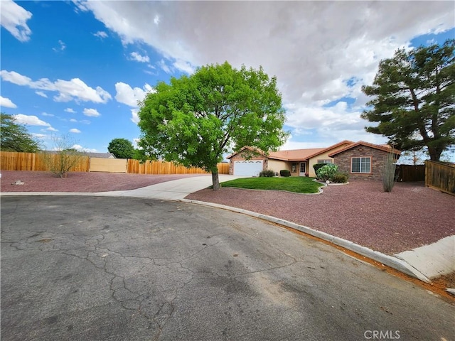 view of front of home with concrete driveway, stone siding, a garage, and fence