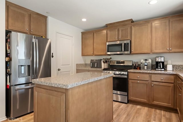 24060 Raptor Way, Lake Elsinore, CA 92532 - kitchen with appliances with stainless steel finishes, light wood finished floors, a kitchen island, recessed lighting, and light stone countertops