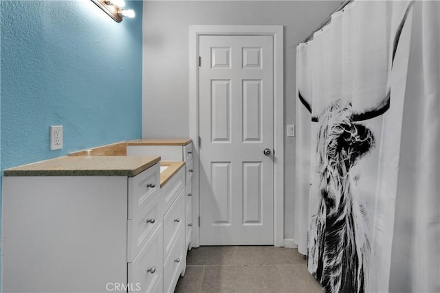 bathroom featuring vanity, a textured wall, and tile patterned floors