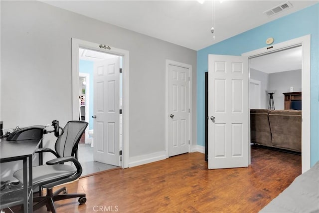 office with baseboards, visible vents, and wood finished floors