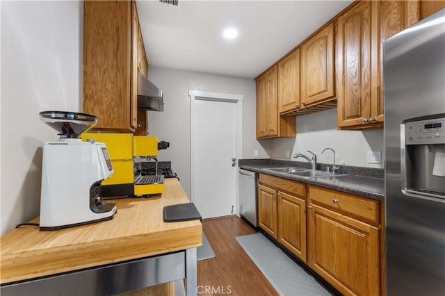 kitchen featuring a sink, wall chimney exhaust hood, brown cabinets, and stainless steel appliances