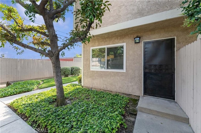 property entrance with fence and stucco siding