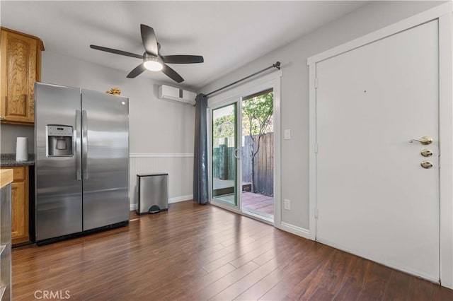 kitchen featuring ceiling fan, a wall mounted AC, brown cabinets, dark wood-style floors, and stainless steel fridge