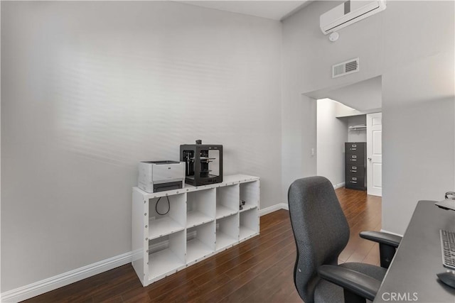 office space with an AC wall unit, baseboards, visible vents, and wood finished floors
