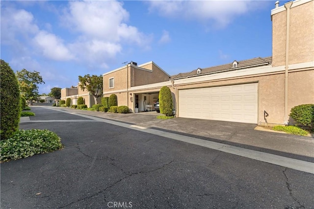 townhome / multi-family property with stucco siding, an attached garage, and aphalt driveway