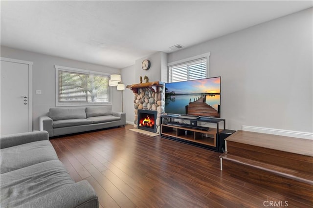 living room featuring wood finished floors, visible vents, a wealth of natural light, and a fireplace