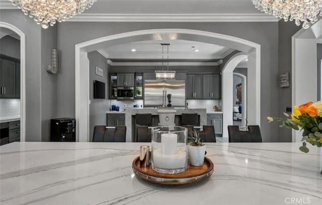 dining space with arched walkways, an inviting chandelier, and ornamental molding