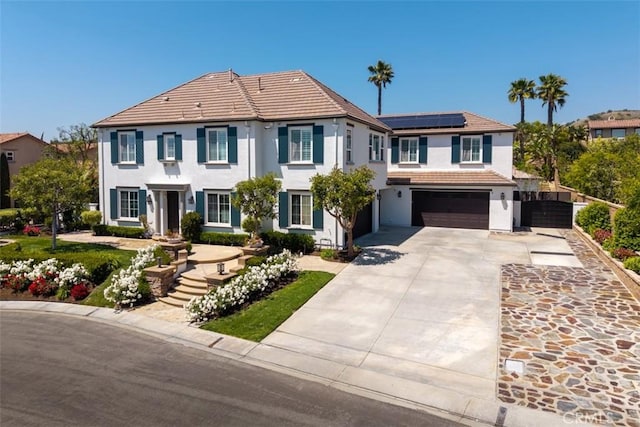 view of front of house with a garage, stucco siding, solar panels, a tiled roof, and driveway