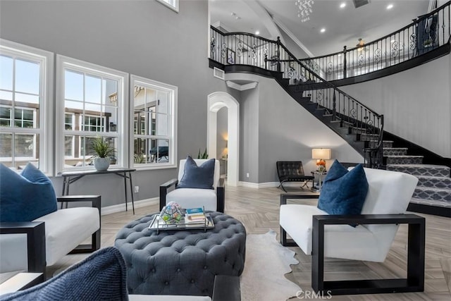 living room with arched walkways, baseboards, a high ceiling, and stairway