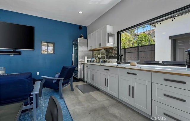 kitchen featuring finished concrete flooring, a wealth of natural light, a sink, and tasteful backsplash