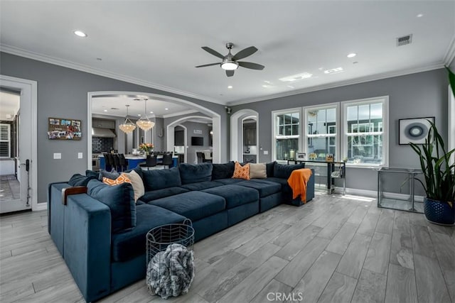 living room with baseboards, arched walkways, light wood-style floors, and ceiling fan with notable chandelier