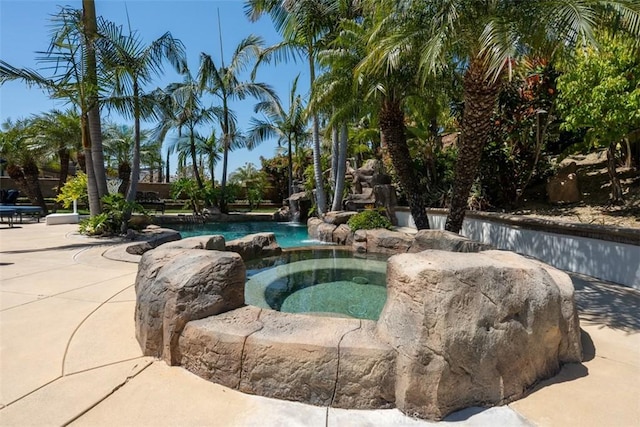 outdoor pool with a patio and an in ground hot tub