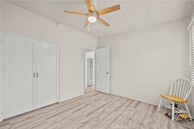 unfurnished bedroom with ceiling fan, a closet, light wood-type flooring, and a textured ceiling