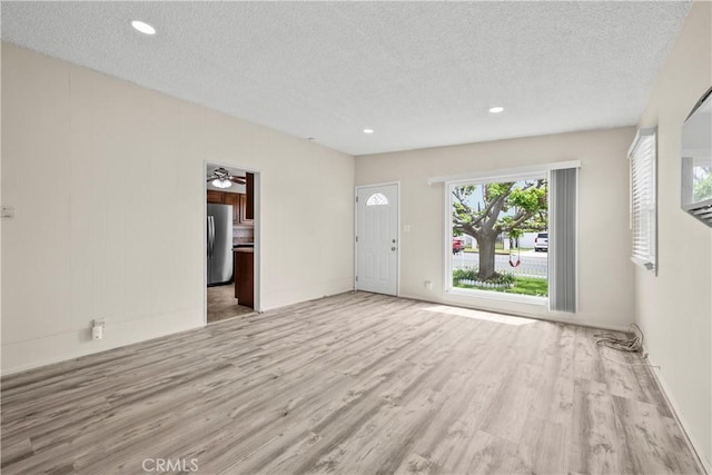 unfurnished living room featuring baseboards, a ceiling fan, a textured ceiling, and wood finished floors