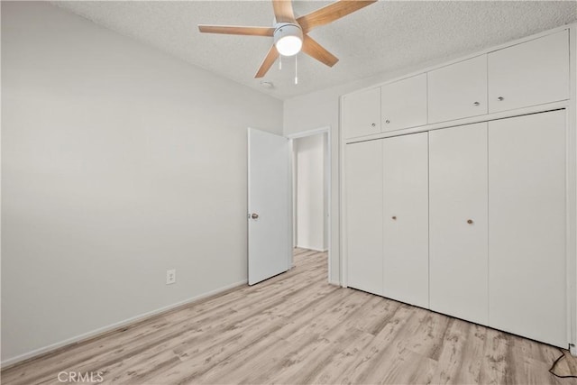 unfurnished bedroom with light wood-type flooring, a textured ceiling, ceiling fan, and a closet