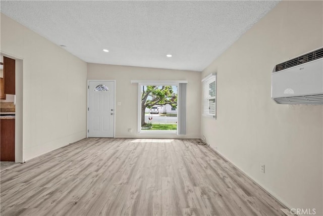 941 N Brand Blvd, San Fernando, CA 91340 - unfurnished living room with light wood-type flooring, a textured ceiling, a wall mounted air conditioner, and recessed lighting
