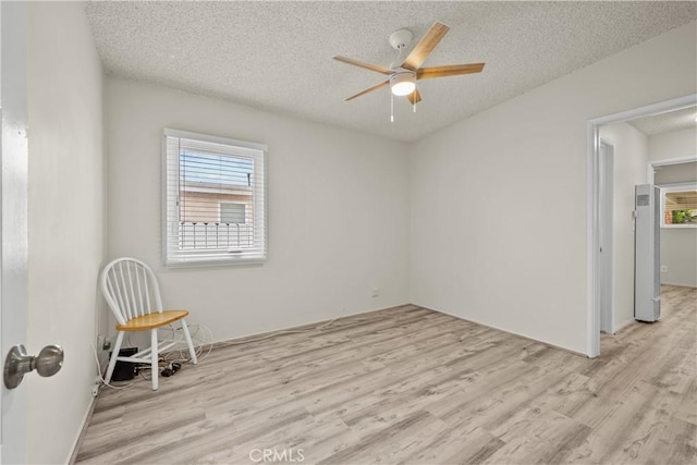 spare room with a ceiling fan, a textured ceiling, and light wood-type flooring