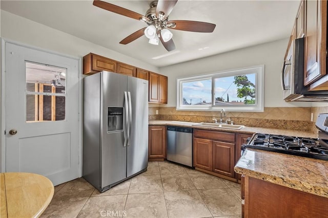 kitchen with a sink, decorative backsplash, appliances with stainless steel finishes, and brown cabinets