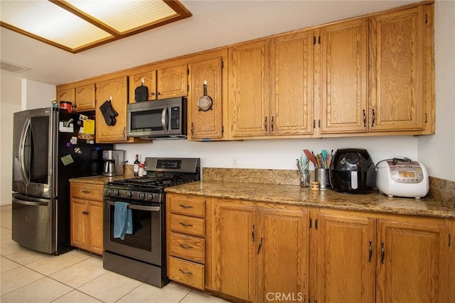 5750 Hall Ln Unit 29, Palms, CA 92277 - kitchen featuring stainless steel appliances, light tile patterned floors, and brown cabinets