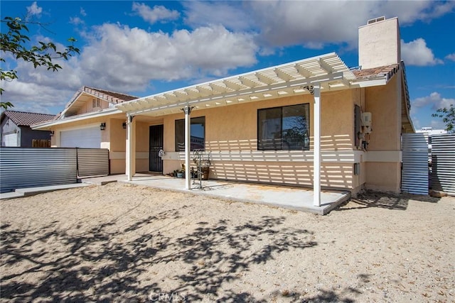 back of property with a chimney, fence, a pergola, an attached garage, and stucco siding