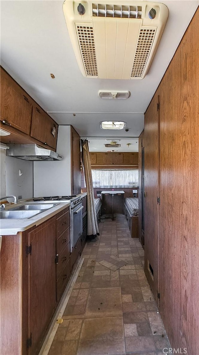 kitchen featuring light countertops, under cabinet range hood, high end stainless steel range, and a sink