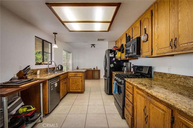kitchen with appliances with stainless steel finishes, light stone counters, a sink, brown cabinetry, and a peninsula