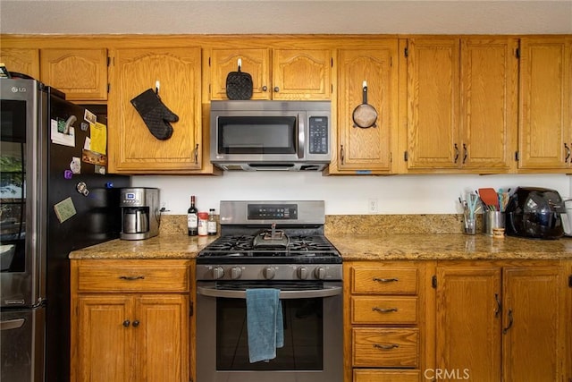 kitchen featuring brown cabinetry, tile patterned flooring, and stainless steel appliances