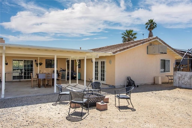 rear view of property with a patio area, stucco siding, and french doors