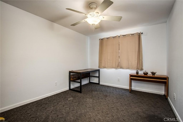 empty room with dark carpet, a ceiling fan, and baseboards