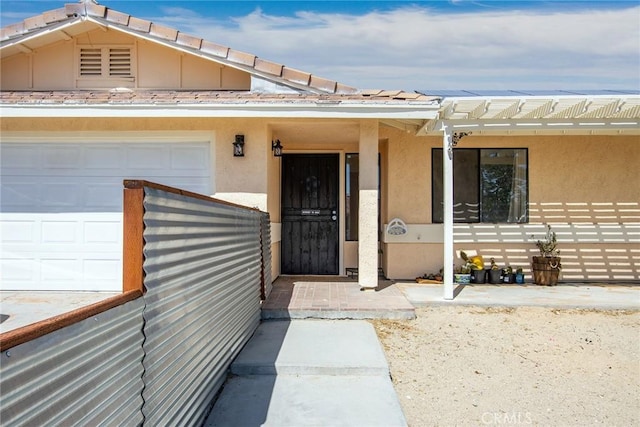 property entrance with a pergola, a garage, and stucco siding