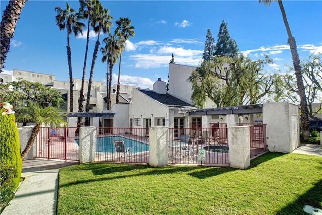 community pool featuring a lawn and fence