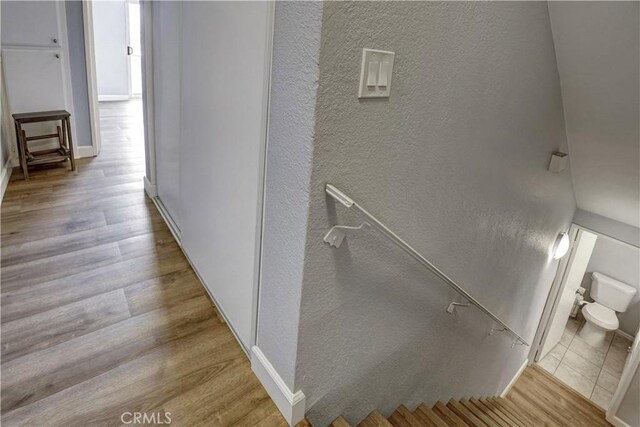 corridor with baseboards, a textured wall, and wood finished floors