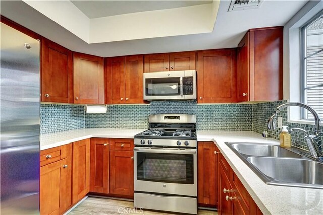 kitchen with light countertops, appliances with stainless steel finishes, a sink, and visible vents