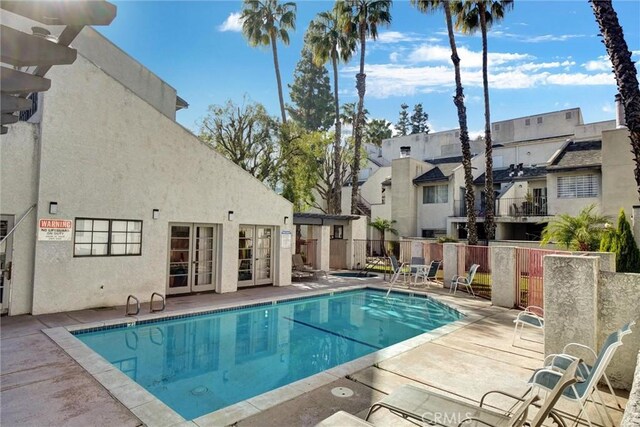 community pool with a patio, a residential view, fence, and french doors