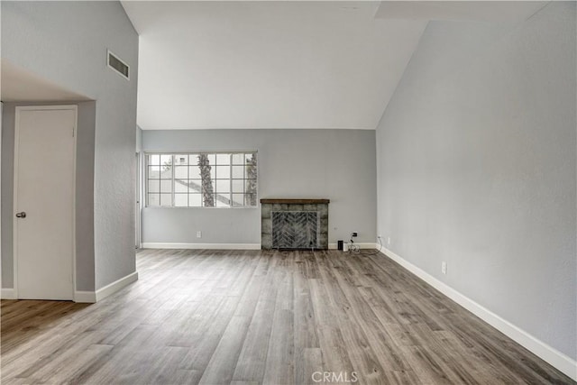 unfurnished living room featuring visible vents, a fireplace, wood finished floors, baseboards, and high vaulted ceiling