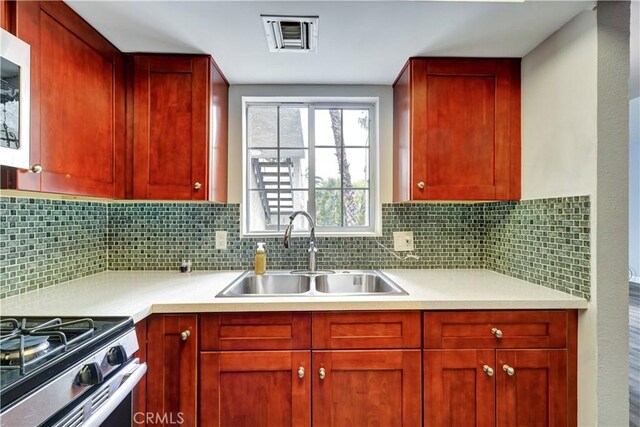 kitchen featuring light countertops, backsplash, visible vents, and a sink