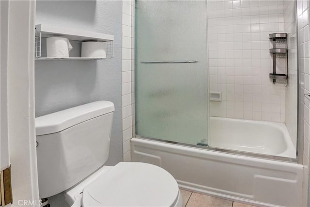 bathroom featuring bath / shower combo with glass door, tile patterned floors, and toilet