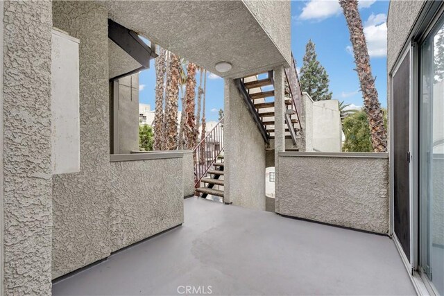 view of patio featuring stairs and a balcony