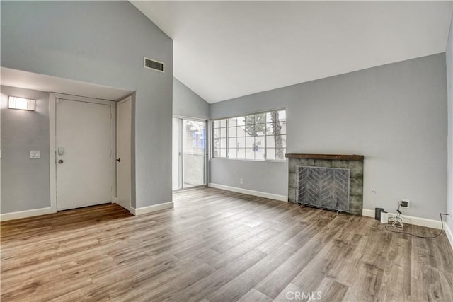 unfurnished living room featuring high vaulted ceiling, visible vents, a tiled fireplace, and wood finished floors
