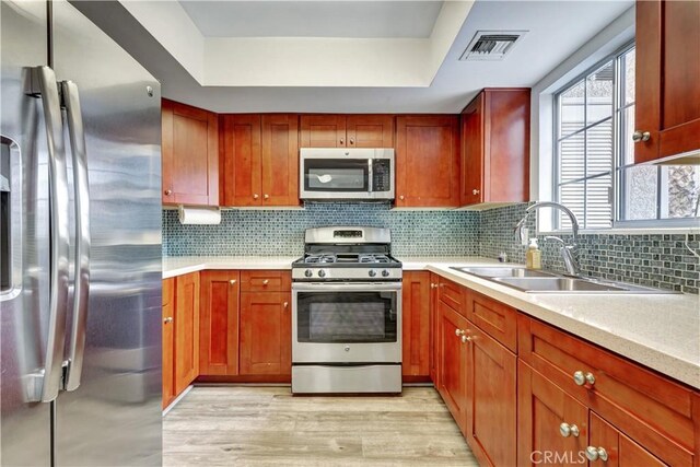 kitchen with a sink, light countertops, stainless steel appliances, light wood-type flooring, and visible vents