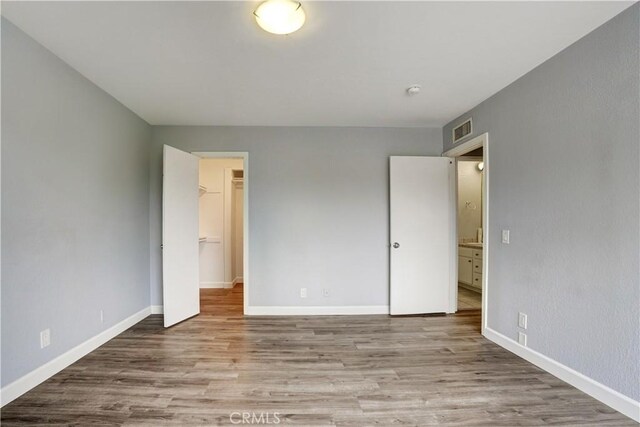 unfurnished bedroom featuring baseboards, wood finished floors, and visible vents