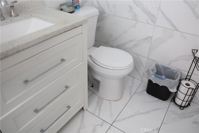 half bath with vanity, marble finish floor, and toilet
